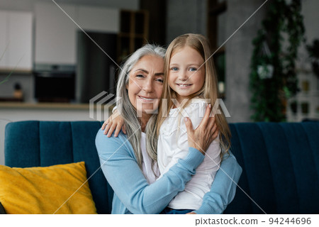 Love and family relationship. Happy european elderly grandmother and little granddaughter hugging Love and family relationship. Happy european elderly grandmother and little granddaughter hugging 94244696