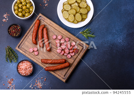 Delicious fresh smoked sausages cut with slices on a wooden cutting board 94245555