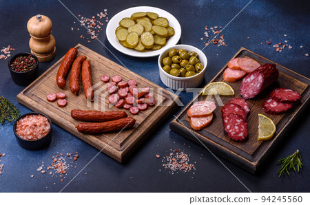 Delicious fresh smoked sausages cut with slices on a wooden cutting board 94245560