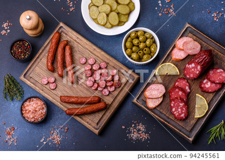 Delicious fresh smoked sausages cut with slices on a wooden cutting board Delicious fresh smoked sausages cut with slices on a wooden cutting board 94245561