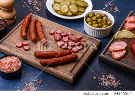 Delicious fresh smoked sausages cut with slices on a wooden cutting board Delicious fresh smoked sausages cut with slices on a wooden cutting board 94245564