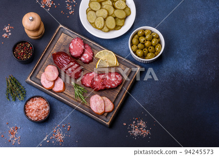Delicious fresh smoked sausages cut with slices on a wooden cutting board Delicious fresh smoked sausages cut with slices on a wooden cutting board 94245573