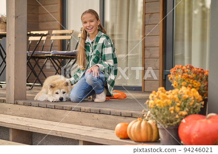 Joyful teen stroking her lovely dog and looking before her 94246021