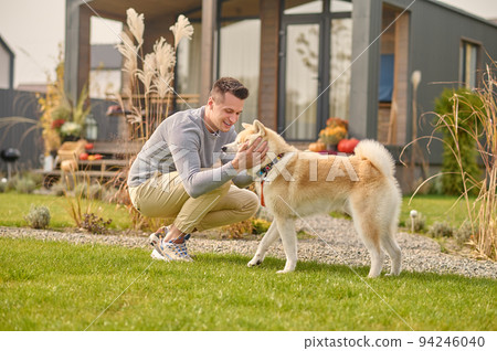 Pleased man and his adorable dog in the backyard Pleased man and his adorable dog in the backyard 94246040
