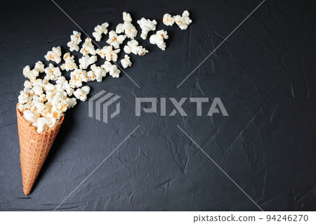 Waffle Cone with Salted Popcorn on black concrete background. Snack concept Waffle Cone with Salted Popcorn on black concrete background. Snack concept 94246270