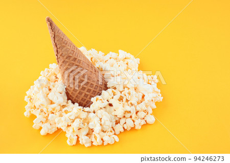 Waffle Cone with Salted Popcorn on yellow background. Snack concept Waffle Cone with Salted Popcorn on yellow background. Snack concept 94246273