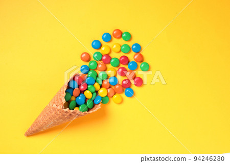 Waffle Cone with Color Candies on yellow background Waffle Cone with Color Candies on yellow background 94246280