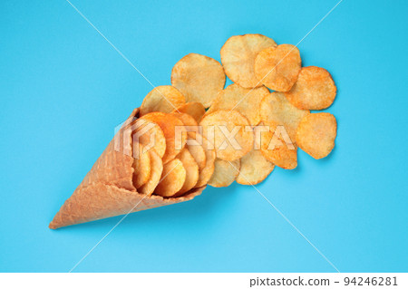 Waffle Cone with Potato Chips on blue background. Fast Food concept Waffle Cone with Potato Chips on blue background. Fast Food concept 94246281