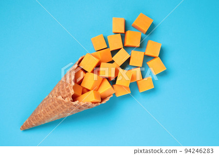 Waffle Cone with Yellow Cheese Cubes on blue background Waffle Cone with Yellow Cheese Cubes on blue background 94246283