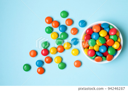 Vessel with Color Candies on blue background Vessel with Color Candies on blue background 94246287