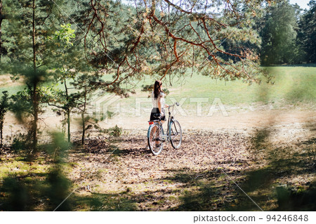 Mental health benefits of cycling, reduce anxiety. Cycling in forest. Forest Bycycle Trails. Single woman riding bike in pine forest in sunny day. Mental health benefits of cycling, reduce anxiety. Cycling in forest. Forest Bycycle Trails. Single woman riding bike in pine forest in sunny day. 94246848