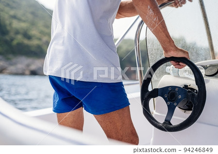 Man in shorts drives a speedboat at sea in Corfu 94246849