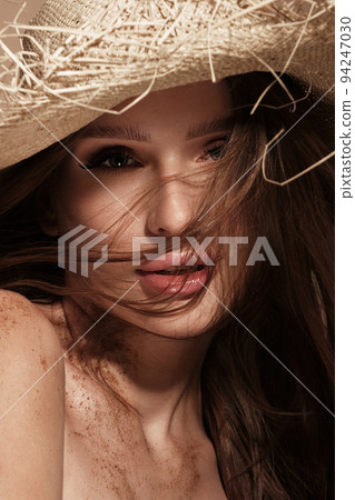 Portrait of a beautiful woman in a straw hat, loose hair and nude makeup. Beauty face Portrait of a beautiful woman in a straw hat, loose hair and nude makeup. Beauty face 94247030