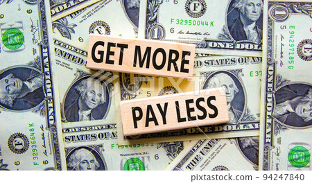 Get more pay less symbol. Concept words Get more pay less on wooden blocks on a beautiful background from dollar bills. Business Get more pay less concept. Copy space. 94247840