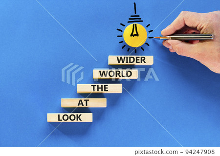 Look at the world wider symbol. Concept words Look at the world wider on wooden blocks on a beautiful blue background. Businessman hand. Business and look at the world wider concept. Copy space. 94247908