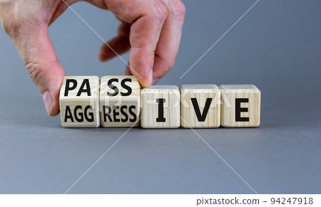 Passive or aggressive symbol. Businessman turns wooden cubes and changes the word passive to aggressive. Beautiful grey background, copy space. Business, psychological passive aggressive concept. 94247918