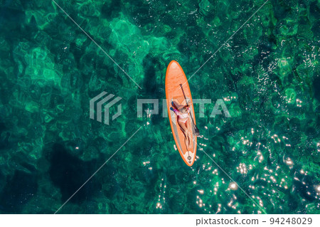 Young women Having Fun Stand Up Paddling in blue water sea in Montenegro. SUP. girl Training on Paddle Board near the rocks Portrait of a disgruntled girl sitting at a cafe table 94248029
