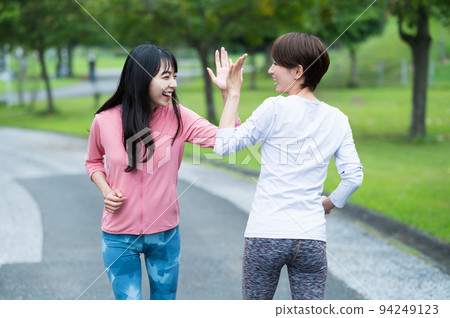 Two women giving a high five while jogging Two women giving a high five while jogging 94249123