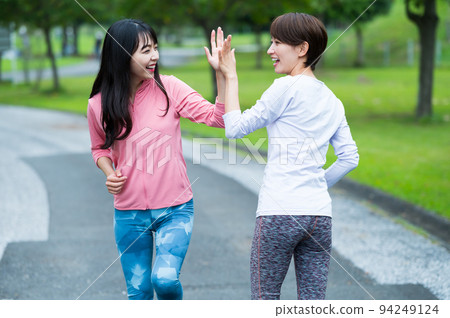 Two women giving a high five while jogging 94249124