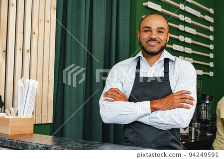 Portrait of a mixed race young man barista in coffee shop Portrait of a mixed race young man barista in coffee shop 94249591