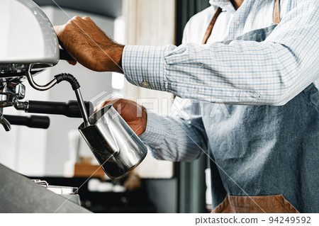 Unrecognizable man barista preparing coffee on professional coffee machine Unrecognizable man barista preparing coffee on professional coffee machine 94249592