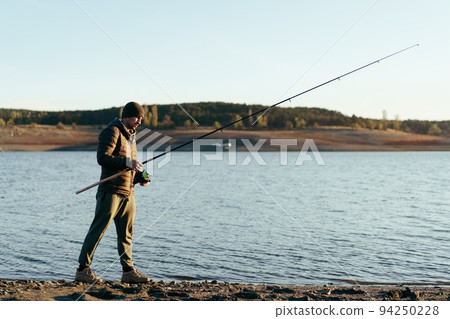 Fisherman with rod fishing on the lake 94250228