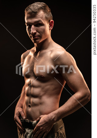 Studio shot of muscular topless military man on black background 94250335