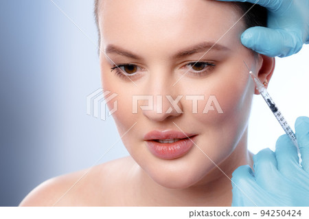 Beautiful woman with short hair gets a beauty injection in her face Beautiful woman with short hair gets a beauty injection in her face 94250424