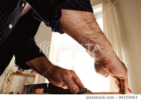 Carpenter makes pencil marks on a wood plank 94250463