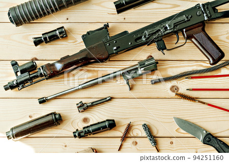 Disassembled rifle with cleaning tools on table of weapons workshop 94251160