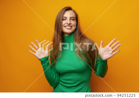 Young pretty surprised smiling woman standing with open palms on yellow background 94251225