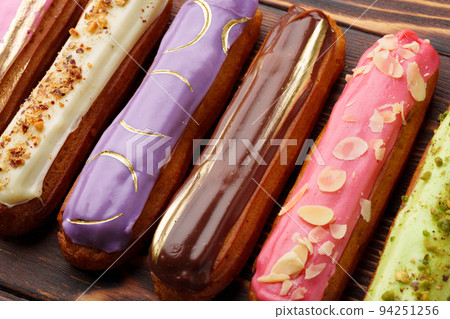 Assortment of sweet and colorful eclairs on wooden background 94251256