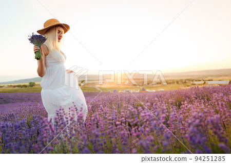 Young woman in long white dress standing in lavender field Young woman in long white dress standing in lavender field 94251285
