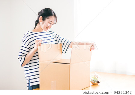 A woman who opens a cardboard with a smile (mail order / home delivery) 94251342