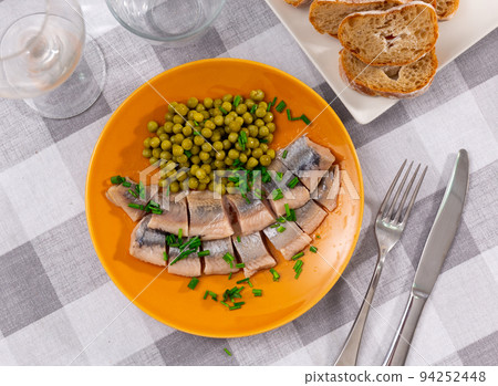 Sliced herring served with scallion and peas on table 94252448