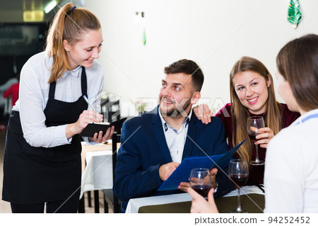 Woman waiter is taking order from clients Woman waiter is taking order from clients 94252452