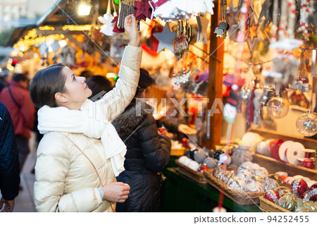 Woman is choosing decorations for Christmas tree in the market 94252455