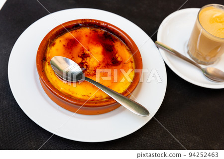 Delicious traditional Spanish dessert - Crema catalana served with spoon in clay bowl Delicious traditional Spanish dessert - Crema catalana served with spoon in clay bowl 94252463