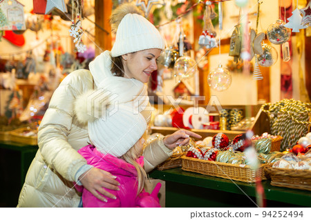 Woman and her daughter are preparing for Christmas and choosing balls on the street market 94252494