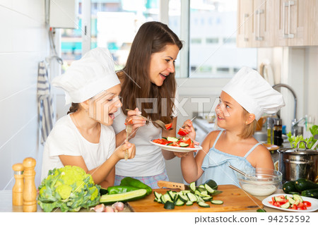 Mother and two daughters eating at kitchen Mother and two daughters eating at kitchen 94252592