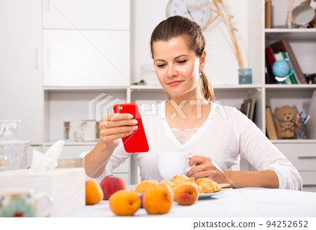 Young female using modern smartphone at home table 94252652