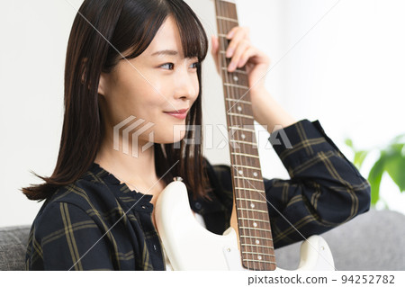 坐在沙發上彈吉他的女人 坐在沙發上彈吉他的女人 94252782