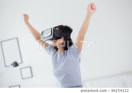 Young asian woman wearing vr headset playing game with excited in the bedroom at home. Young asian woman wearing vr headset playing game with excited in the bedroom at home. 94254222