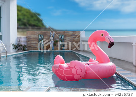 Pink inflatable flamingo on swimming pool. Concept for summer day 94256727