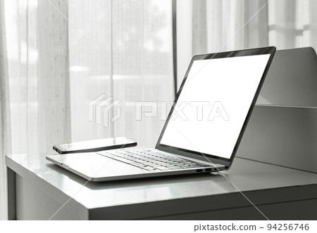 Computer laptop with blank screen and smartphone on white table in home interior 94256746