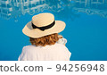 woman holds a white cup of coffee in her hands on the background of a blue swimming pool. Good 94256948