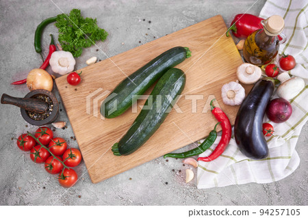 zucchini on wooden cutting board and vegetables at domestic kitchen 94257105