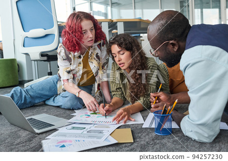Two young confident women pointing at financial document during discussion 94257230