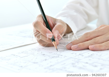 The hand of the designer who checks the drawing 94260307