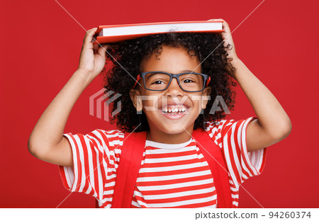 Happy ethnic schoolboy laughing and playing with book Happy ethnic schoolboy laughing and playing with book 94260374